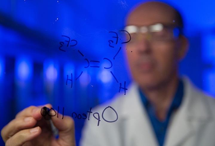 Employee writing chemical compounds on a clear board