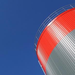 gray and red storage tank against a blue sky