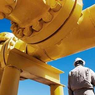 oil refinery worker standing next to yellow pipeline