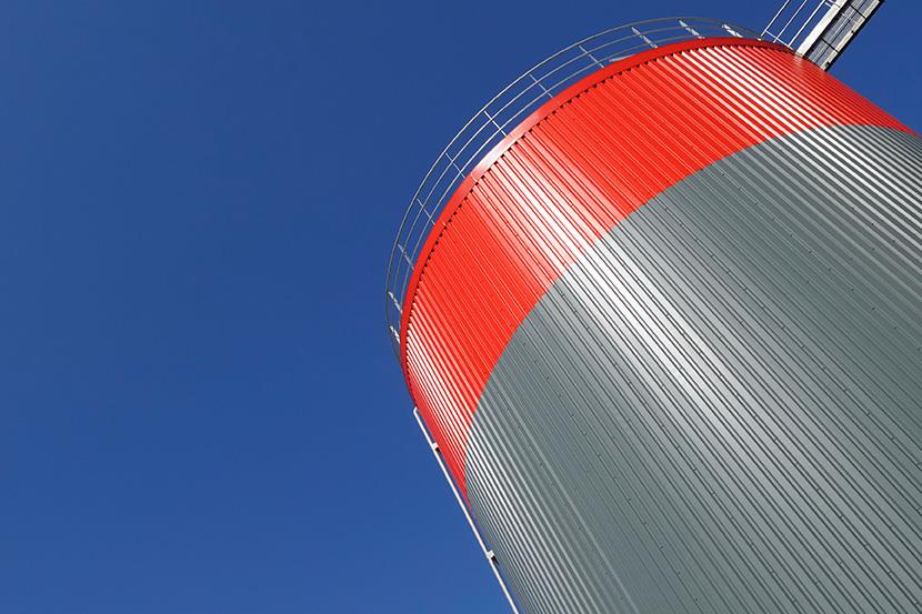 gray and red storage tank against a blue sky